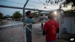 A manager at the Christian Aid Ministries headquarters, left, speaks with a worker at the door of the center in Titanyen, north of Port-au-Prince, Haiti, Sunday, Nov. 21, 2021. (AP Photo/Odelyn Joseph)
