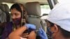 A woman receives a dose of Covishield, the Oxford-AstraZeneca vaccine for COVID-19 in her car at a drive-in vaccination facility in Ahmedabad, India, May 28, 2021.