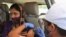 A woman receives a dose of Covishield, the Oxford-AstraZeneca vaccine for COVID-19 in her car at a drive-in vaccination facility in Ahmedabad, India, May 28, 2021.