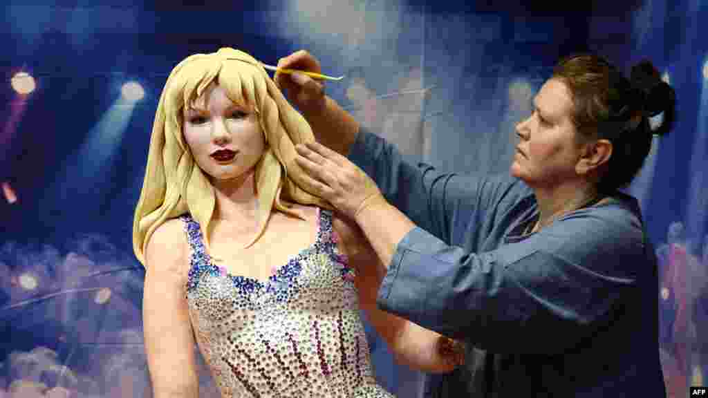 A cake artist works on her creation of singer Taylor Swift after it was damaged in transit en route to the Cake International show ain Birmingham, England.