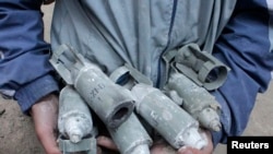 한 소년이 시리아 정부군이 알레포에 제트기 폭격을 가한 후 폭발되지 않은 집속탄 파편 폭탄들을 수거해 보여주고 있다. 