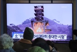 FILE - People watch a TV screen showing a file image of a ground test of North Korea's rocket engine during a news program at the Seoul Railway Station in Seoul, South Korea, Dec. 9, 2019.