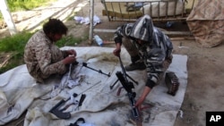 Foto yang dirilis pada 16 Juni 2015, oleh pendukung ISIS menunjukkan militan ISIS membersihkan senapan mereka di kota Deir el-Zour, Suriah.