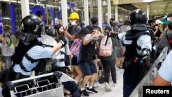 8月13日，防暴警察使用胡椒水驱散反送中大游行的抗议者。在此之前，一名女性抗议者在香港国际机场的集会中眼部受伤。