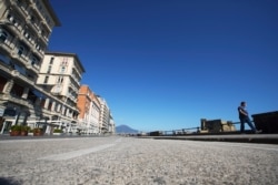 A man walks along Naples promenade, Italy, Monday, April 27, 2020. Italian factories, construction sites and wholesale supply businesses can resume activity as soon as they put safety measures into place aimed at containing contagion with COVID-19.