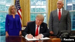 도널드 트럼프 대통령이 20일, 마이크 펜스 부통령과 커스텐 닐슨 국토안보부 장관이 지켜보는 가운데 불법 이민자 가족의 격리를 막는 행정명령에 서명하고 있다.