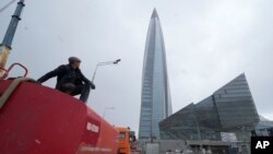 FILE - A worker sits on his water tank truck next to the business tower Lakhta Centre, the headquarters of Russian gas monopoly Gazprom in St. Petersburg, Russia, April 27, 2022. 