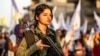 A member of the Kurdish Internal Security Police Force of Asayish stands guard as Syrian Kurdish demonstrate against Turkish threats to invade the Kurdish region, in the northeastern city of Qamishli, Aug. 27, 2019. 