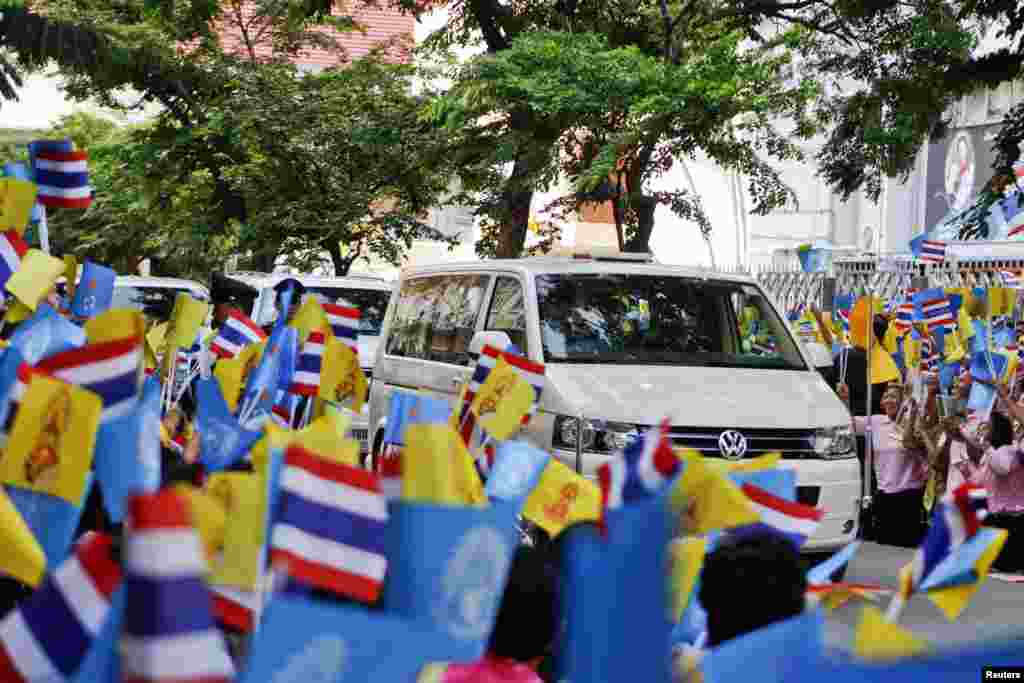 People wave flags as Thailand's King Bhumibol Adulyadej's motorcade leaves Siriraj hospital in Bangkok, August 1, 2013.
