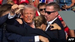 ترامپ پس از تیراندازی به او در ایالت پنسیلوانیا و در حالی که خون روی صورتش است در میان محافظان قرار گرفت