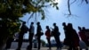 FILE - Migrants stand stand in line at a respite center after they crossed the U.S.-Mexico border and turned themselves in and were released in Del Rio, Texas, June 16, 2021.
