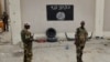 Des soldats nigérians se tiennent à un poste de contrôle devant un drapeau de Boko Haram la ville de Damasak, Nigeria, 18 mars 2015.