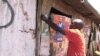 An activist pastes an election campaign poster in the Kibera slum of Nairobi, Kenya (G. Joselow/VOA).