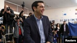 Pemimpin kubu oposisi dari partai Syriza, Alexis Tsipras, tersenyum sebelum memasukkan suaranya di sebuah TPS di Athena (25/1).