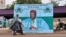 Des femmes passent devant une affiche de campagne de l'ancien président du Niger et candidat à la présidence, Mahamane Ousmane, le 18 février 2021 à Niamey.
