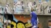 An Egyptian woman passes by a wall with defaced posters of presidential candidates in Cairo, Egypt, Monday, May, 21, 2012.
