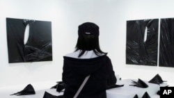 In this March 25, 2016 photo, a woman looks at an installation artwork created by Chinese artist Stella Zhang at Art Basel in Hong Kong.