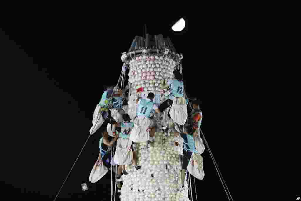 Participants climb the bun tower during the bun-snatching competition on the outlying Cheung Chau island in Hong Kong, to celebrate the Bun Festival. During the festival, the Taoist God of the Sea is worshiped, and evil spirits are scared away by loud gongs and drums during the procession.