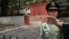 A paramilitary police officer gestures outside the Belgium embassy in Beijing, June 19, 2019. A Belgian diplomat was to travel to China's Xinjiang region June 18 to confirm the whereabouts of a Uighur family escorted from Belgium's embassy in Beijing by police last month.