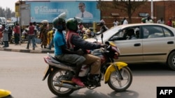 FILE - A passenger rides on a moto-taxi in Kigali, Rwanda, July 30, 2017. Rwanda is introducing electric motorcycles, with more than 600 being built for use in the country.