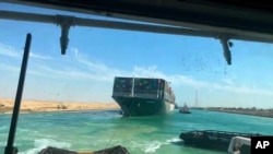FILE - In this photo released by Suez Canal Authority, the Ever Given, a Panama-flagged cargo ship is accompanied by Suez Canal tugboats as it moves in the Suez Canal, Egypt, March 29, 2021.