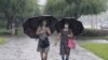 Women walk with umbrellas during torrential rains, Aug. 5, 2020, in Pyongyang. North Korea says torrential rains have lashed the country, prompting outside worries about possible severe damages in the impoverished country. 