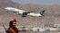 FILE - A Taliban fighter stands guard as a Pakistan International Airlines plane, the first commercial international flight to land since the Taliban retook power, takes off at the airport in Kabul on Sept. 13, 2021.