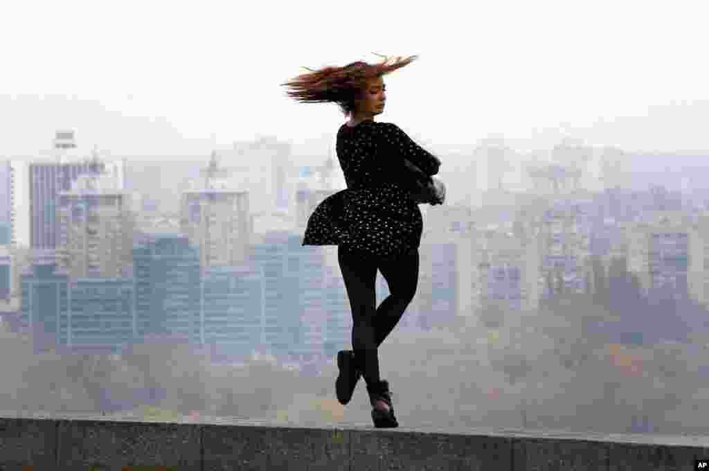 The wind blows a girl's dress as she looks upon the banks of the Dnipro River in Kyiv, Ukraine, Nov. 6, 2017.