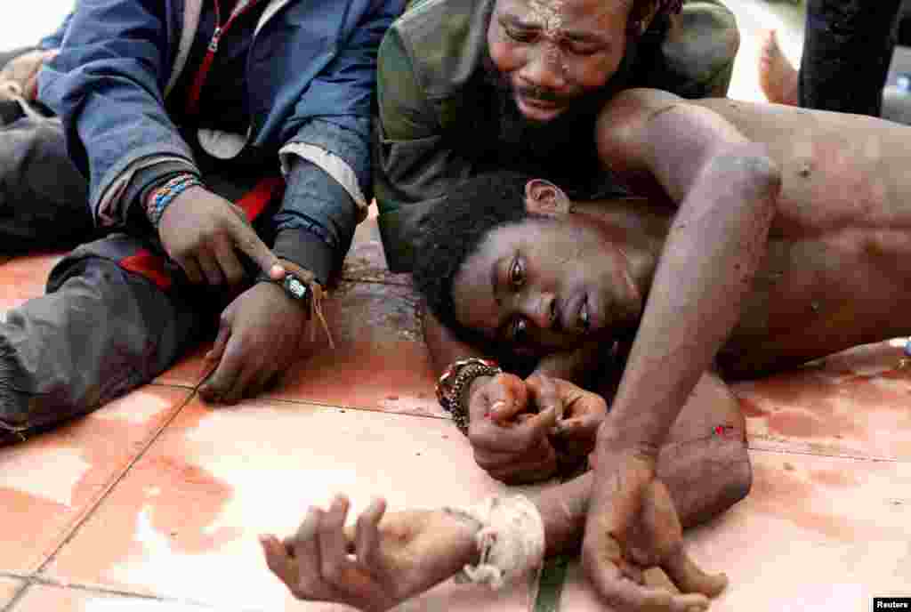 Beberapa pria migran Afrika kelelahan setelah menyeberangi perbatasan Ceuta, Spanyol dari Maroko.