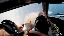 Pilot pesawat Australia, Lt. Jayson Nichols mengamati peta saat menerbangkan pesawat AP-3C Orion untuk upaya pencarian pesawat Malaysia Airlines MH370 di atas Samudera Hindia (27/3).