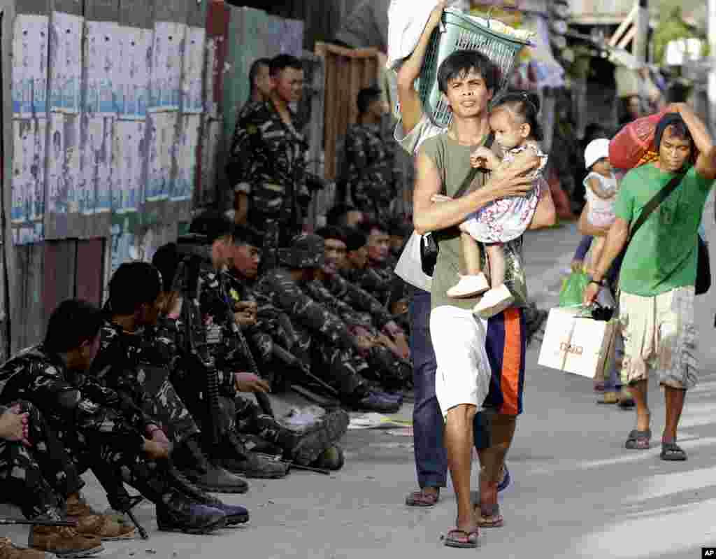 Warga meninggalkan rumah-rumah mereka sambil membawa barang-barang mereka di tengah pertempuran di Zamboanga, Filipina (11/9). (AP/Bullit Marquez)