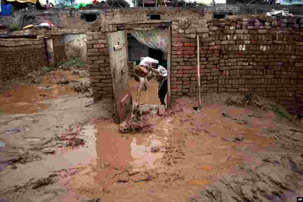 A Pakistani empties a bucket of muddy water from his home flooded by heavy rains in Peshawar, Pakistan, August 3, 2013.&nbsp;