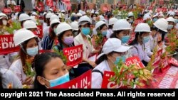 2021年2月21日在曼德勒举行的反政变游行中，医学院学生戴着口罩，举着标语牌聚集在一起。