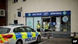 Des policiers britanniques montent la garde devant une succursale de la pharmacie Boots à Amesbury, en Angleterre, le 4 juillet 2018.