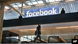 FILE - The Facebook logo is displayed in a startup companies gathering at Paris' Station F, Jan. 17, 2017.