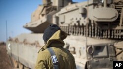 이스라엘 군인이 시리아 국경 골란 고원에서 탱크 옆에 서있다.