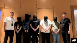 资料照片：2023年8月26日，在缅甸仰光国际机场，缅甸警方将5名电信网络诈骗犯罪嫌疑人移交给中国警方。(Chinese embassy in Myanmar/Xinhua via AP)