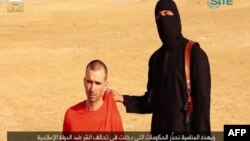 伊斯兰国恐怖主义组织发布的一段视频显示，一名蒙面的武装人员威胁要将英国人大卫·海恩斯斩首。本图为视频截图