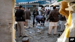 Pakistani security officials examine the site of a suicide attack in Mardan, Pakistan, Dec. 29, 2015.