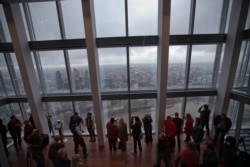 FILE - Visitors look at the sights during the official opening of "The View" viewing platform at the Shard skyscraper in London.