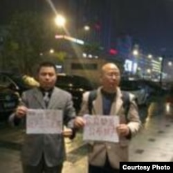 王成（左）举牌要求官员公示财产(王成律师推特)