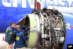 National Transportation Safety Board investigators examine damage to the engine of the Southwest Airlines plane that made an emergency landing at Philadelphia International Airport, April 17, 2018. The engine blew at 32,000 feet.