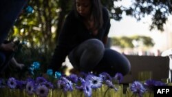 Amnesty International activists place flowers outside the Russian Consulate in protest against the persecution of gay men in Chechnya, in Sao Paulo, Brazil on June 16, 2017. / AFP PHOTO / Miguel SCHINCARIOL