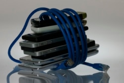 Foto ilustrasi ponsel-ponsel pintar yang dililit kabel jaringan internet, 7 Juni 20213. (Foto: Reuters)