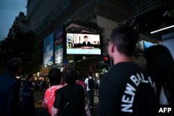 Pedestrians look at a large monitor display showing a news broadcast of Hong Kong Chief Executive Carrie Lam announcing she will permanently shelve a controversial extradition bill in Hong Kong on September 4, 2019.