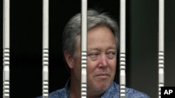 2013年6月25日，美国佛罗里达州专用医疗用品公司共同业主斯塔恩斯从窗外眺望。因工资纠纷，他被愤怒的北京怀柔分厂工人扣为人质。