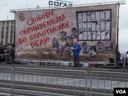 一名男子在莫斯科支持政治犯集会上演讲。他身后的背景是被关押和流亡的政治犯照片，幕墙上的字是释放去年5月6日示威的被捕人士。（美国之音白桦拍摄）