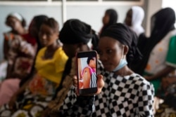 Oumie Nyassi shows a video circulating on the internet and that has been confirmed as fake news of a woman claiming she was magnetized after receiving the COVID-19 vaccine, in a doctors office at Serrekunda, Gambia hospital, Sept. 23, 2021.