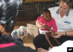 Occupational therapist Shannon Morgan holds one of her young patients while a relative looks on
