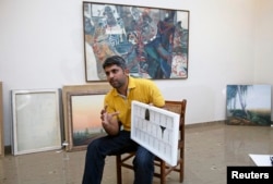 Imran Mudassar, 31, a fine art teacher, shows his latest piece Government College University in Lahore, March 22, 2013.